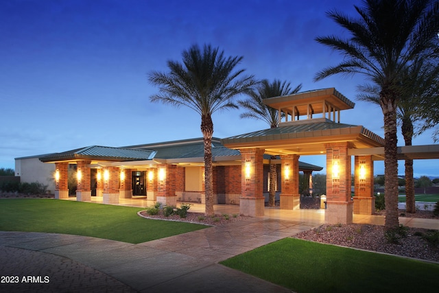 exterior space with brick siding, a standing seam roof, covered porch, a yard, and metal roof