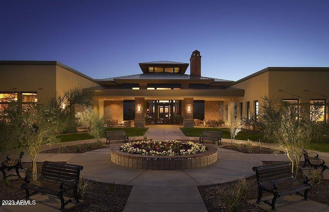 back of house at dusk with metal roof, a chimney, and a standing seam roof
