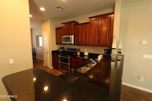 kitchen featuring visible vents, baseboards, a sink, dark stone countertops, and stainless steel appliances