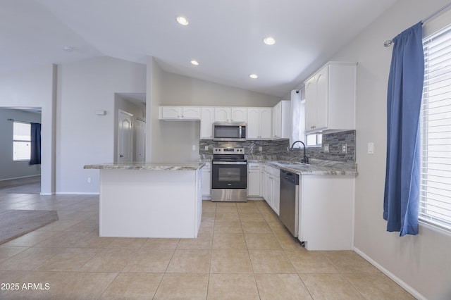 41388 W Hopper Dr, Maricopa, AZ 85138 - kitchen featuring appliances with stainless steel finishes, a sink, vaulted ceiling, decorative backsplash, and light stone counters