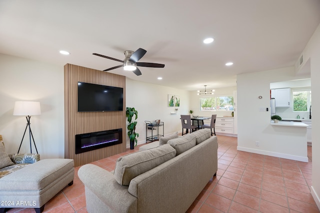 living room featuring ceiling fan with notable chandelier, a wealth of natural light, light tile patterned floors, and a fireplace