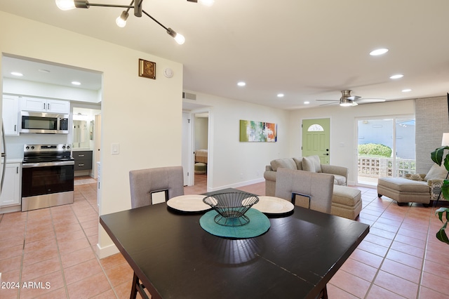 tiled dining space featuring ceiling fan with notable chandelier