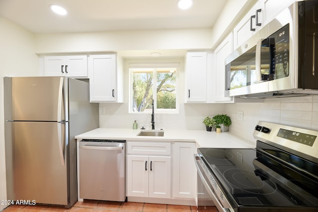 kitchen featuring light tile patterned floors, appliances with stainless steel finishes, sink, and white cabinetry