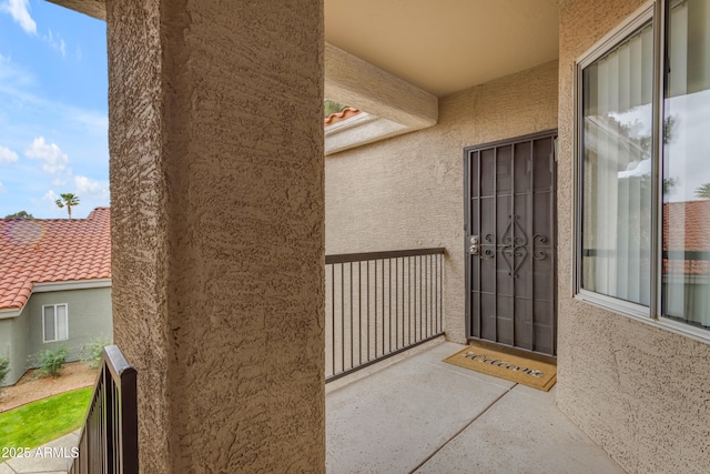 doorway to property featuring a tiled roof, a balcony, and stucco siding