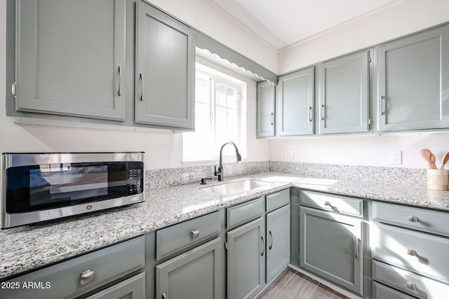 kitchen featuring light stone countertops, gray cabinets, and sink