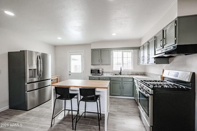 kitchen with a breakfast bar, a center island, wood counters, sink, and stainless steel appliances