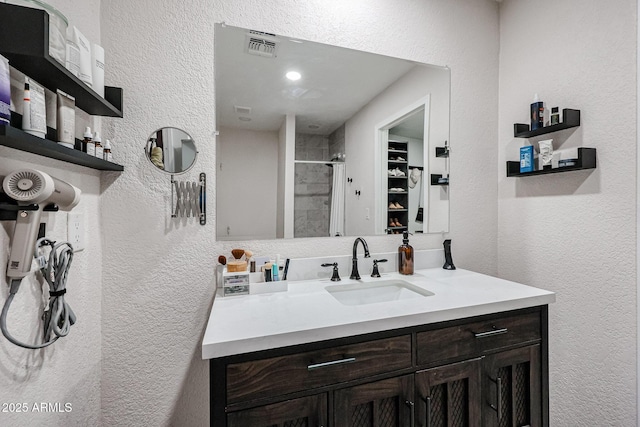 bathroom featuring a tile shower and vanity