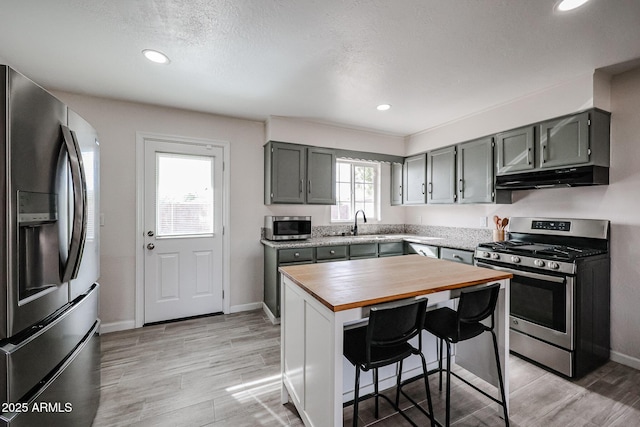 kitchen with wood counters, appliances with stainless steel finishes, a wealth of natural light, and a breakfast bar area