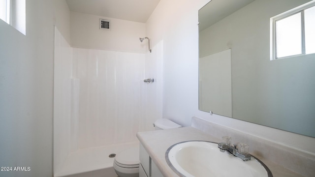 bathroom featuring vanity, toilet, and walk in shower