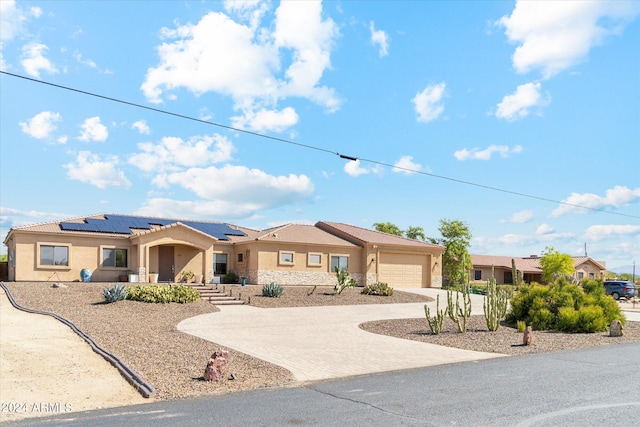 single story home with a garage and solar panels