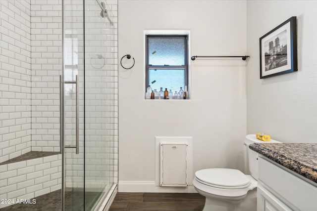 bathroom with wood-type flooring, a shower with door, vanity, and toilet