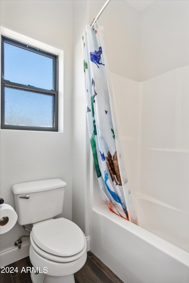 bathroom with wood-type flooring, shower / bathtub combination with curtain, and toilet