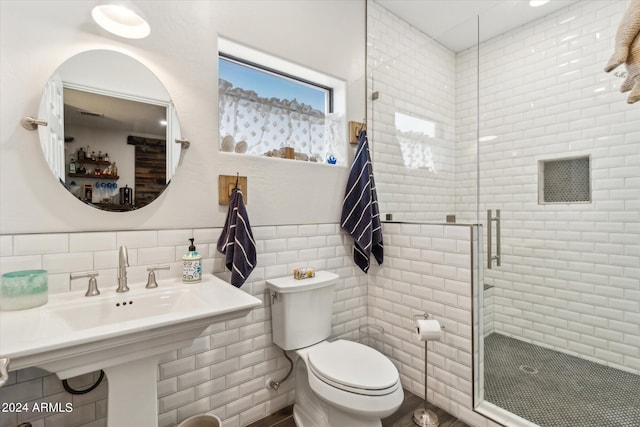 bathroom with tile walls, toilet, and an enclosed shower