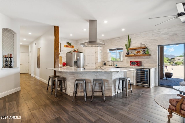 kitchen featuring beverage cooler, a breakfast bar area, stainless steel fridge with ice dispenser, and ventilation hood