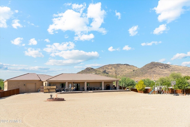 view of front facade featuring a playground, a mountain view, and a fire pit