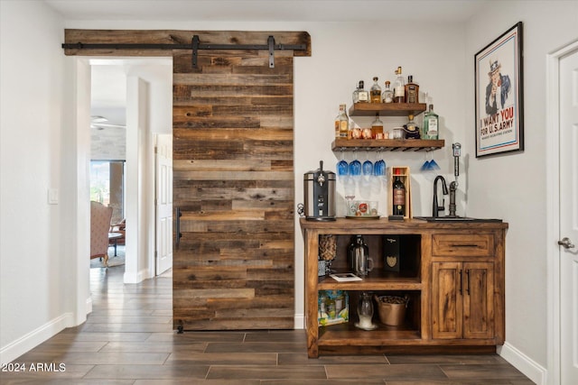 bar with ceiling fan, sink, dark hardwood / wood-style floors, and a barn door