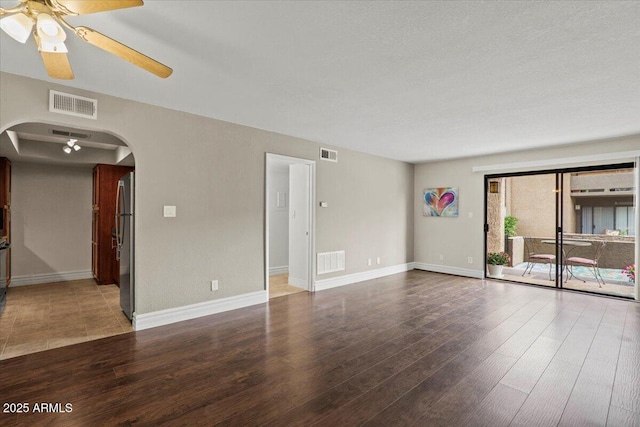 spare room featuring arched walkways, ceiling fan, and visible vents