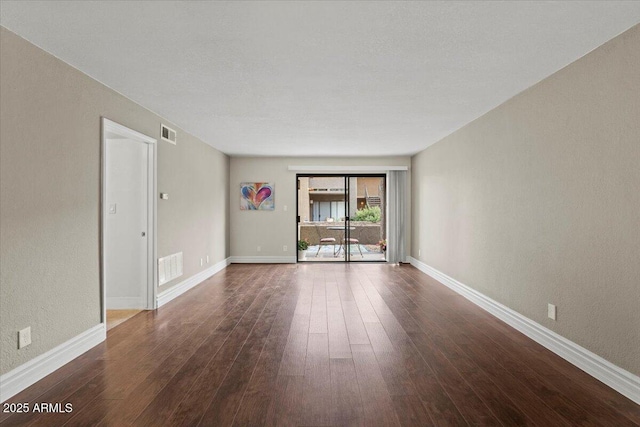 spare room with dark wood-style flooring, baseboards, and visible vents