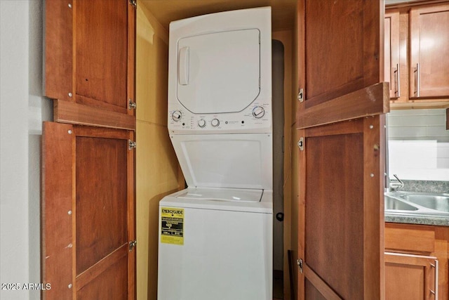 clothes washing area with stacked washer and dryer, laundry area, and a sink