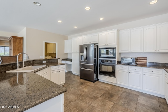 kitchen with stainless steel appliances, sink, dark stone countertops, and white cabinets