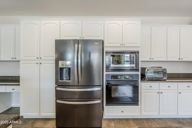 kitchen featuring appliances with stainless steel finishes, dark stone countertops, and white cabinets