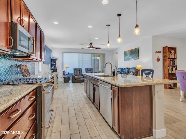 15817 S 177th Dr, Goodyear, AZ 85338 - kitchen with stainless steel appliances, open floor plan, a sink, light wood-type flooring, and backsplash