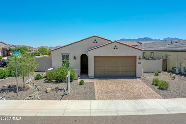15817 S 177th Dr, Goodyear, AZ 85338 - mediterranean / spanish house featuring stucco siding, an attached garage, a tile roof, decorative driveway, and a mountain view