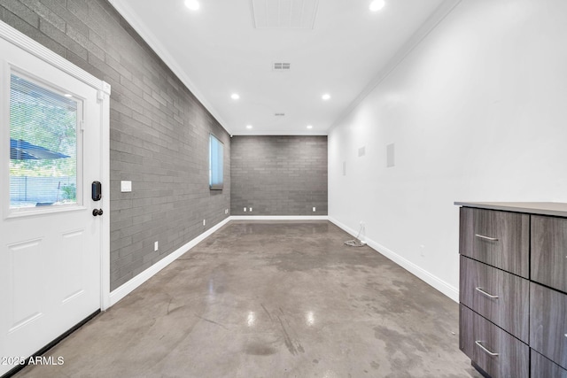1208 E Tuckey Ln, Phoenix, AZ 85014 - empty room featuring crown molding, finished concrete flooring, healthy amount of natural light, brick wall, and recessed lighting