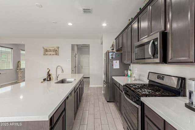 12357 W Whyman Ave, Avondale, AZ 85323 - kitchen featuring appliances with stainless steel finishes, a sink, an island with sink, light countertops, and dark brown cabinets