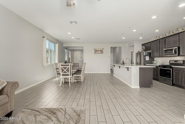 12357 W Whyman Ave, Avondale, AZ 85323 - kitchen featuring stainless steel appliances, baseboards, a center island with sink, a kitchen bar, and recessed lighting