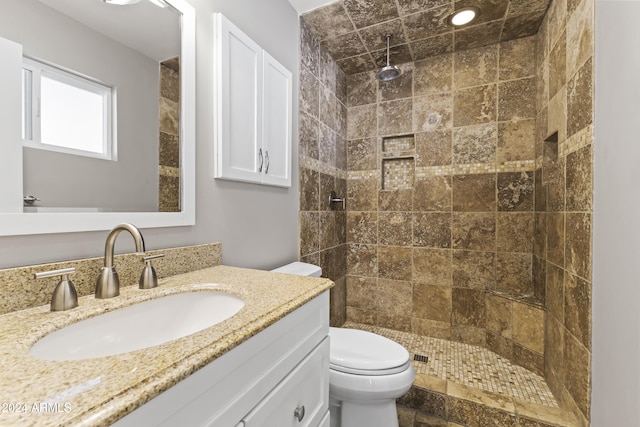 bathroom with toilet, vanity, and tiled shower