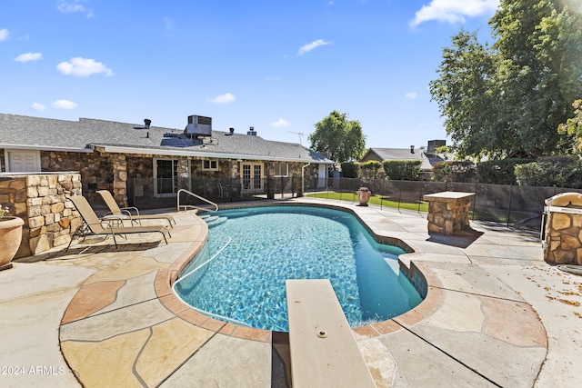 view of swimming pool featuring a patio and a diving board