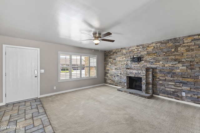 unfurnished living room with a stone fireplace and ceiling fan