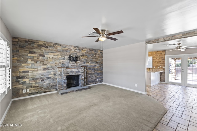 unfurnished living room with french doors, a fireplace, light colored carpet, and ceiling fan