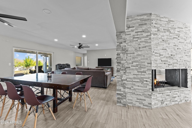 dining room featuring a fireplace, light hardwood / wood-style flooring, and ceiling fan