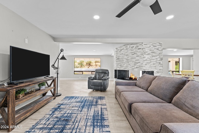 living room with a fireplace, light hardwood / wood-style flooring, and ceiling fan