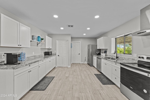 kitchen featuring white cabinetry, sink, light stone counters, appliances with stainless steel finishes, and light wood-type flooring