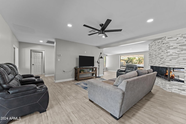 living room with ceiling fan, a multi sided fireplace, and light wood-type flooring