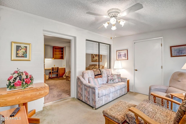 living room featuring ceiling fan, light colored carpet, and a textured ceiling