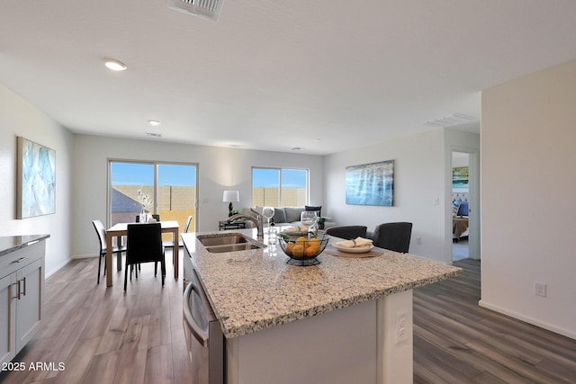 kitchen with a center island with sink, white cabinets, sink, stainless steel dishwasher, and wood-type flooring