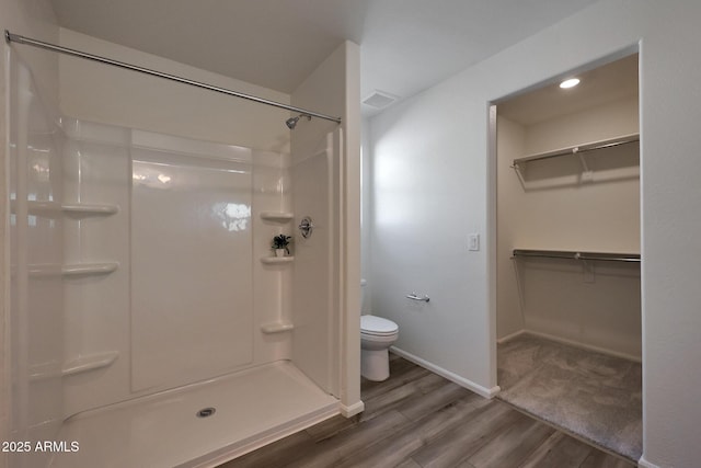 bathroom with hardwood / wood-style floors, toilet, and walk in shower