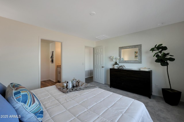 bedroom featuring ensuite bath and light colored carpet