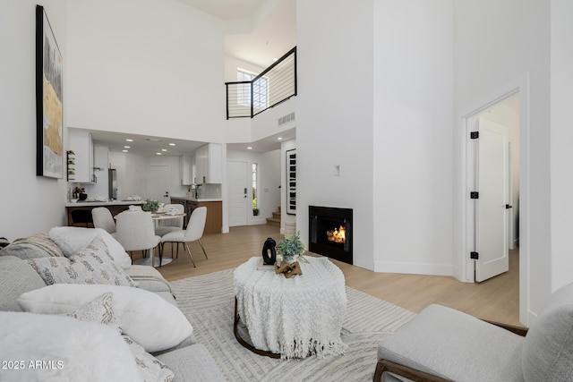 7710 E Gainey Ranch Rd E Unit 115, Scottsdale, AZ 85258 - living area featuring light wood finished floors, a towering ceiling, and a lit fireplace