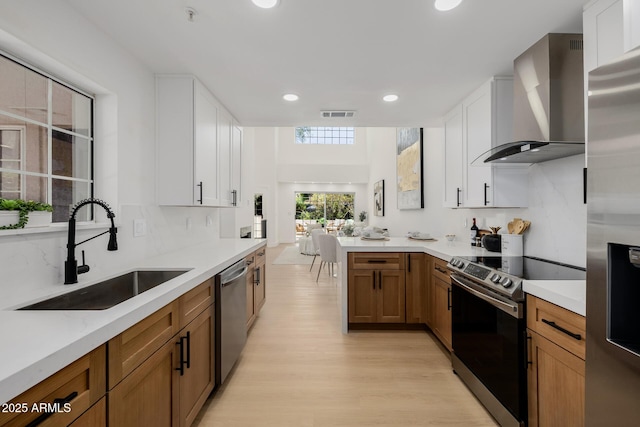 7710 E Gainey Ranch Rd E Unit 115, Scottsdale, AZ 85258 - kitchen featuring wall chimney exhaust hood, stainless steel appliances, light wood-style flooring, light countertops, and recessed lighting