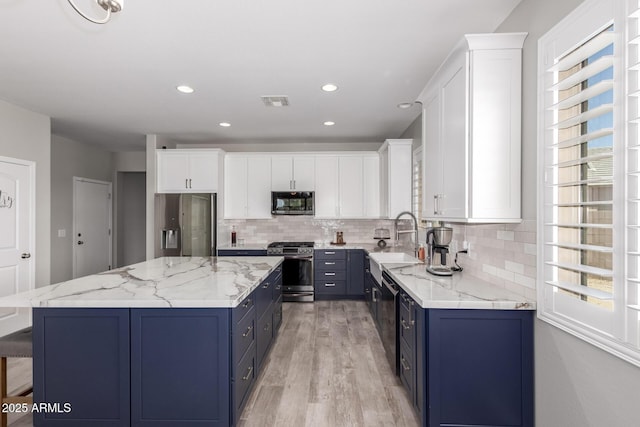 40913 W Williams Way, Maricopa, AZ 85138 - kitchen with appliances with stainless steel finishes, blue cabinetry, backsplash, a kitchen island, and white cabinetry