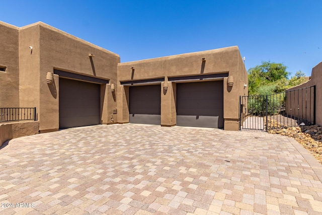 view of front of property with a garage, decorative driveway, fence, and stucco siding