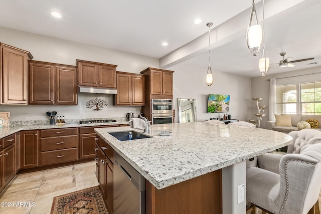 kitchen with a breakfast bar area, a kitchen island with sink, sink, and appliances with stainless steel finishes