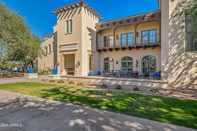 rear view of property featuring outdoor lounge area, a patio area, a balcony, and a lawn