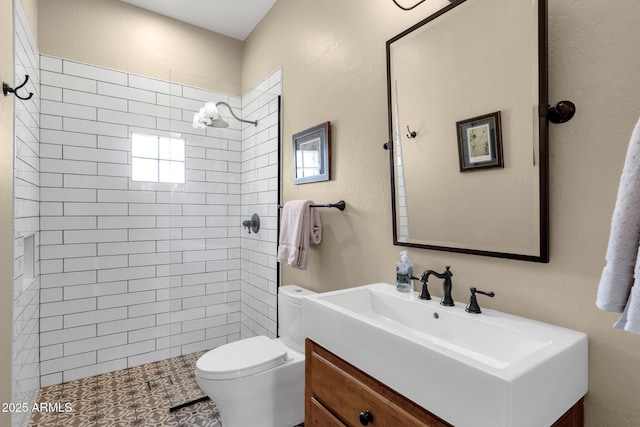 bathroom featuring vanity, toilet, and a tile shower