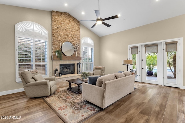 living area featuring a wealth of natural light, a fireplace, high vaulted ceiling, and wood finished floors